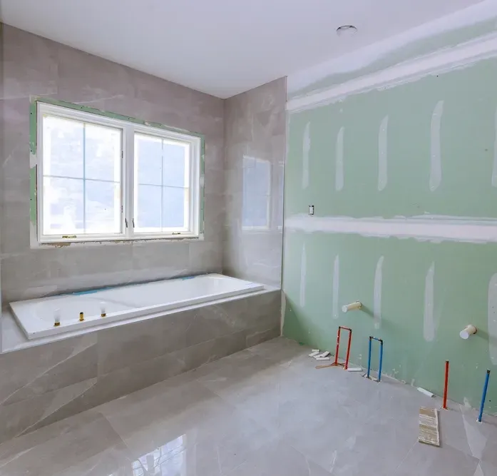 A Bathroom Being Renovated with Gree Plasterboard Walls and Exposed Plumbing — Canberra Bathroom Solutions in Ngunnawal, ACT