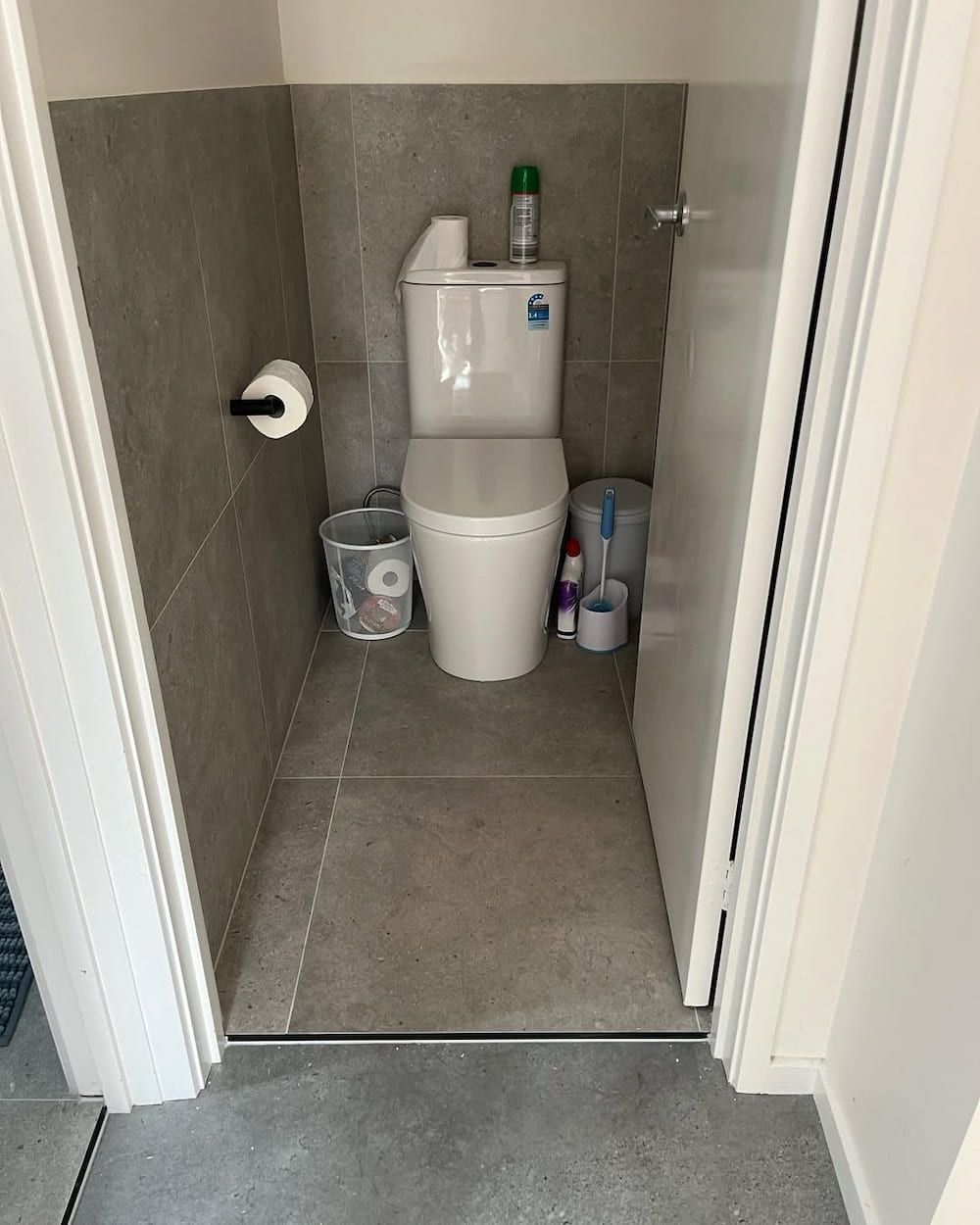 A Toilet is Sitting in a Small Bathroom Next to a Door — Canberra Bathroom Solutions in Ngunnawal, ACT