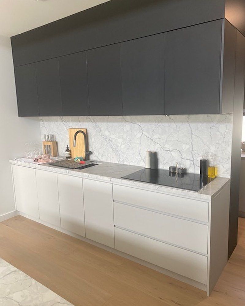 A Kitchen With Black Cabinets and White Drawers and a Stove Top Oven — Canberra Bathroom Solutions in Gungahlin, ACT