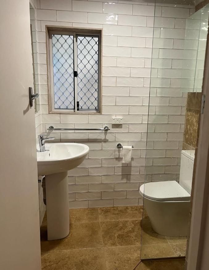 Bathroom With White Textured Tile Walls, Pedestal Sink, Toilet, Window, And Light Brown Floor — Canberra Bathroom Solutions in Ngunnawal, ACT