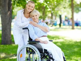 elderly woman in wheelchair and caregiver holding hands