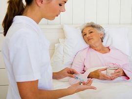 overnight caregiver tending to older woman in bed