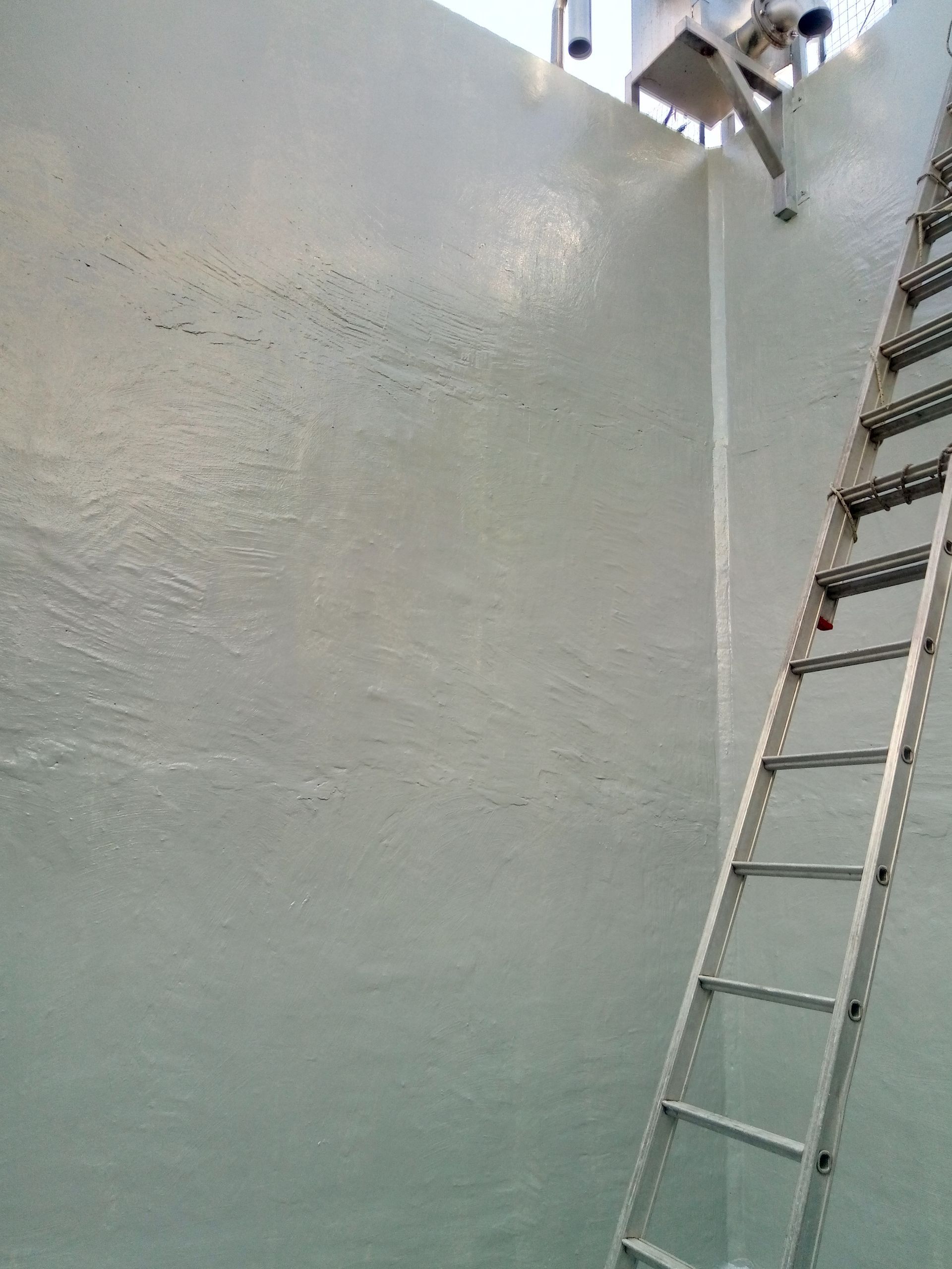 Parete interna verde chiaro con scala metallica. Lampada a sospensione.