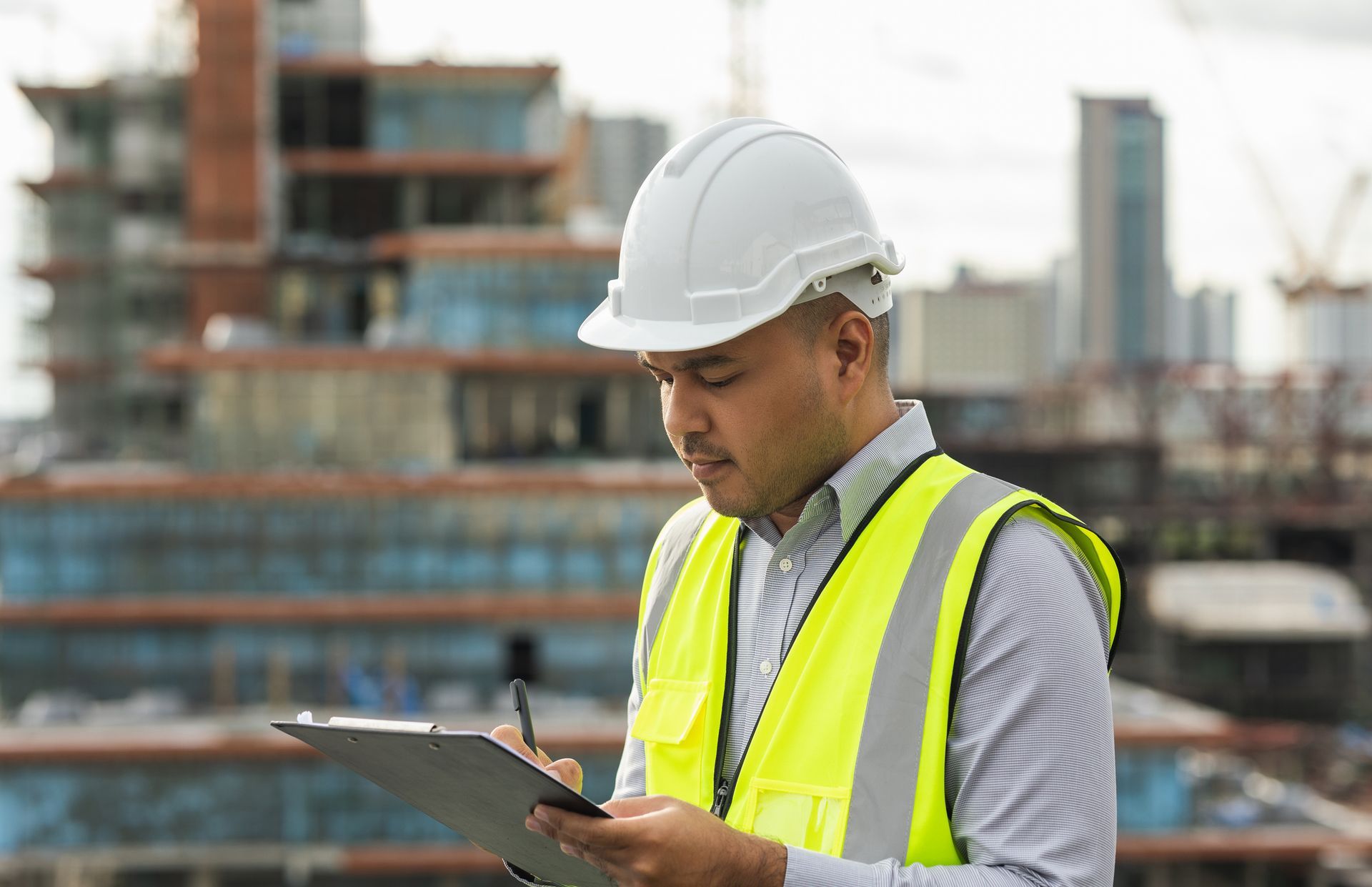 A man wearing a hard hat and safety vest is looking at commercial roof inspection