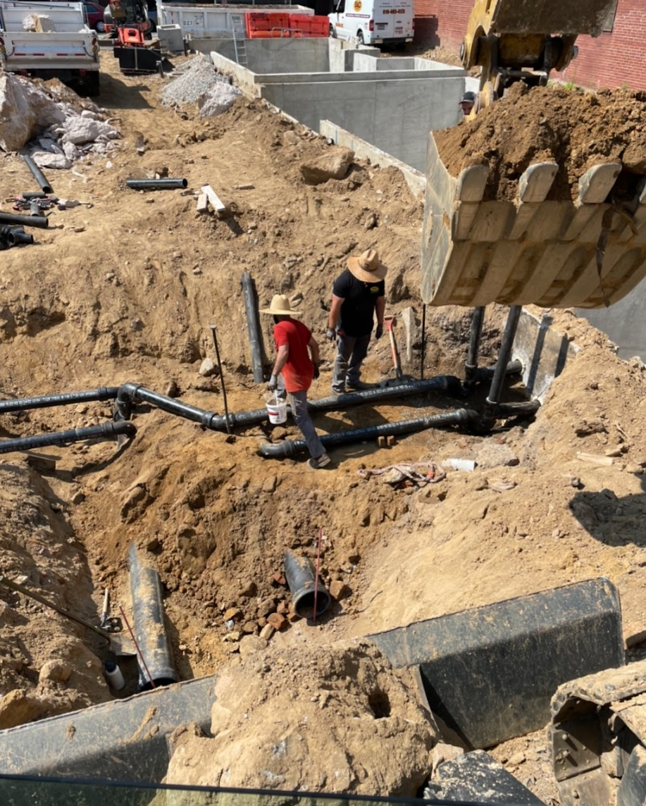 Multi-story apartment building with blue and gray siding, trees, and a walkway on a sunny day.