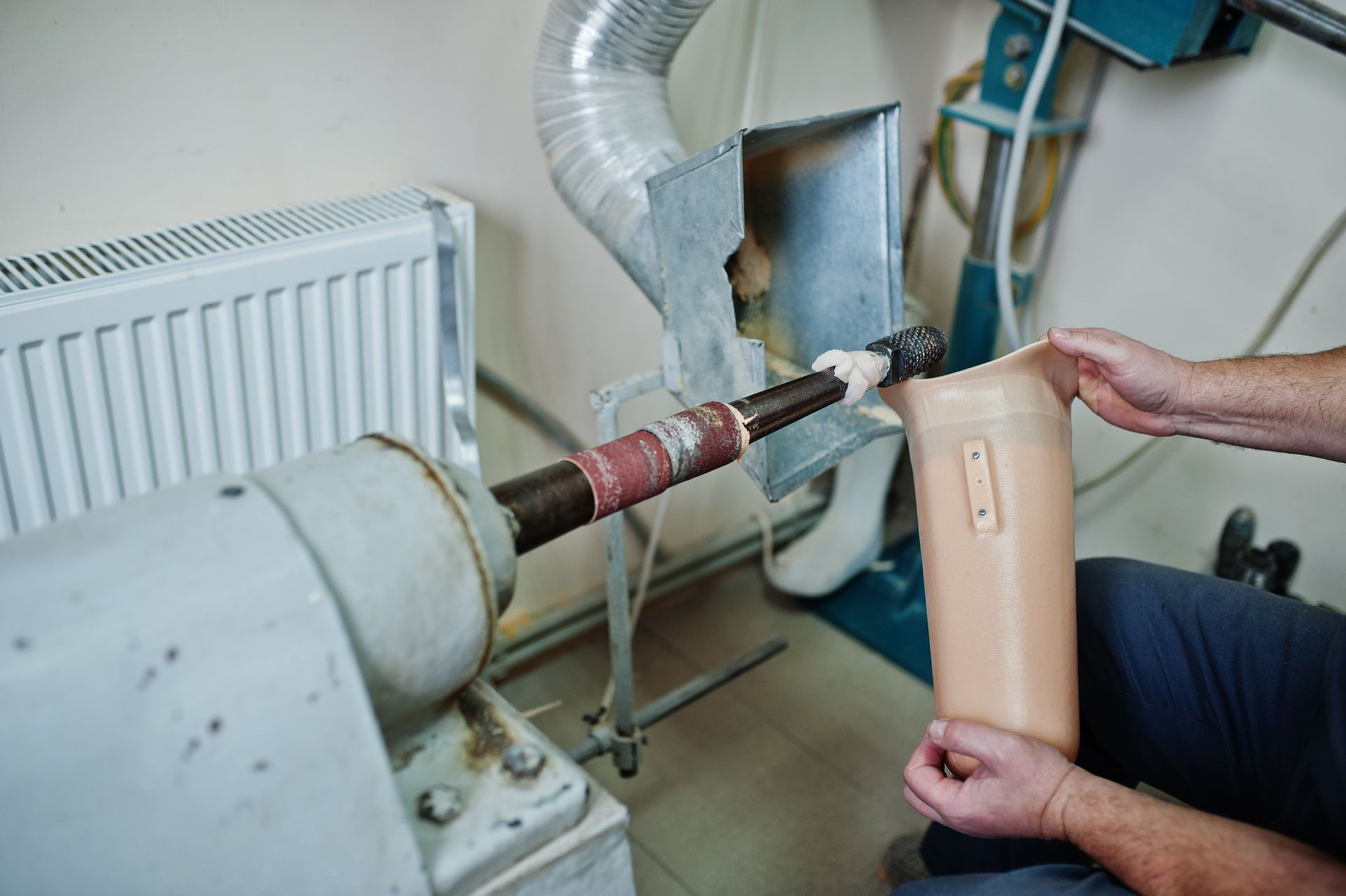 Person fitting prosthetic leg on a machine in a workshop.