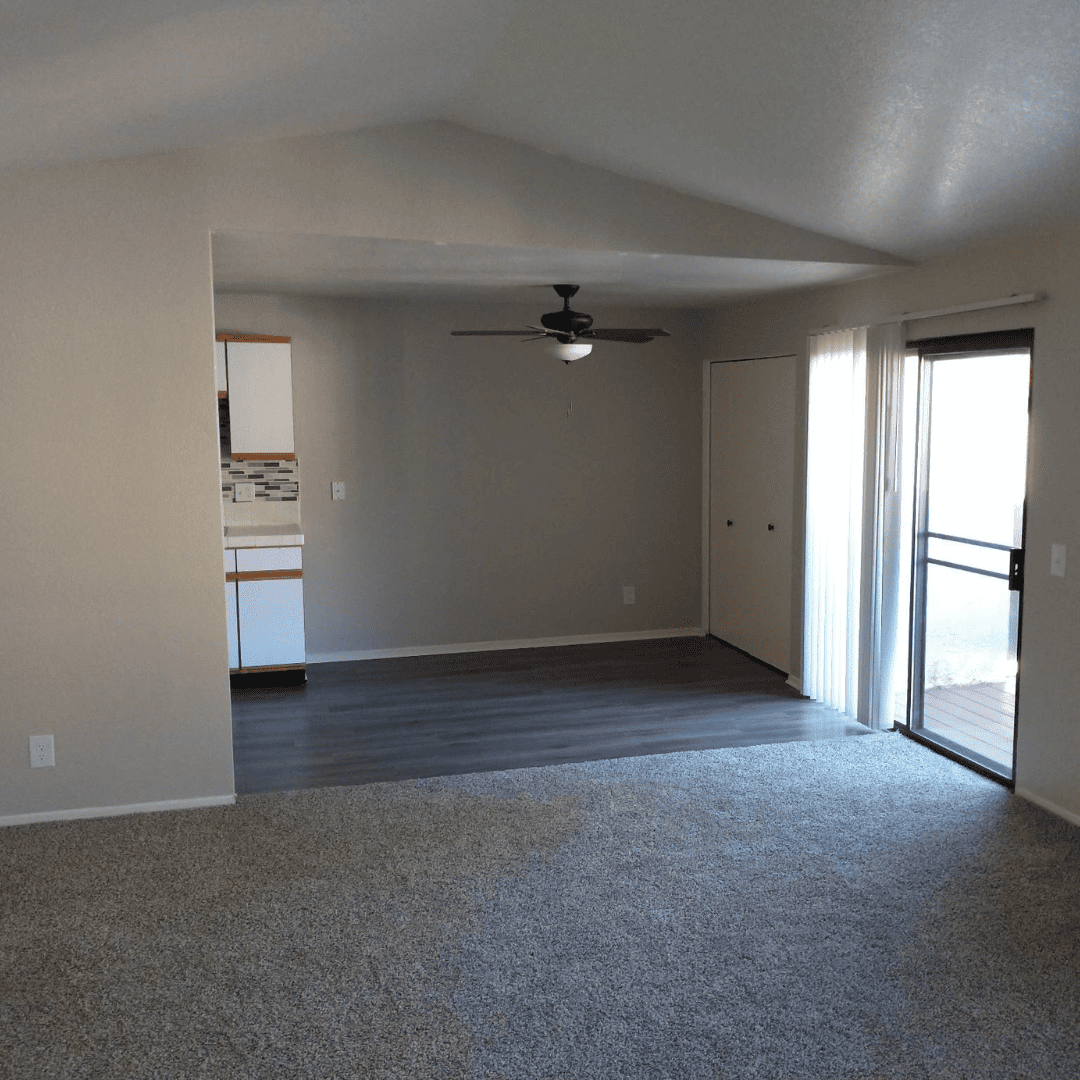 Living room with dark gray carpet, light gray walls, and a sliding glass door.