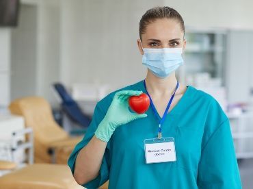 A picture of a female hair transplant surgeon holding a red apple