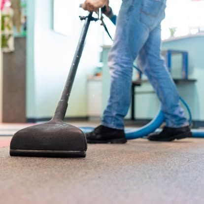 A person is using a vacuum cleaner to clean a carpet.