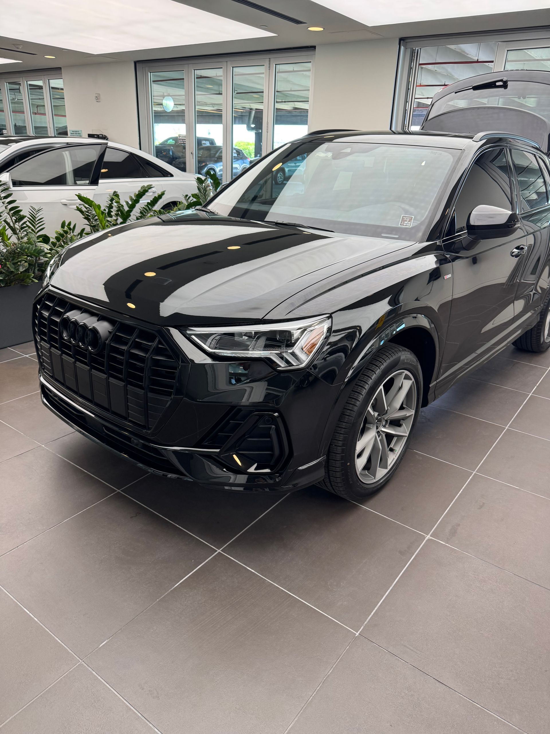 Black Audi Q3 SUV displayed indoors; gray wheels and black grille.
