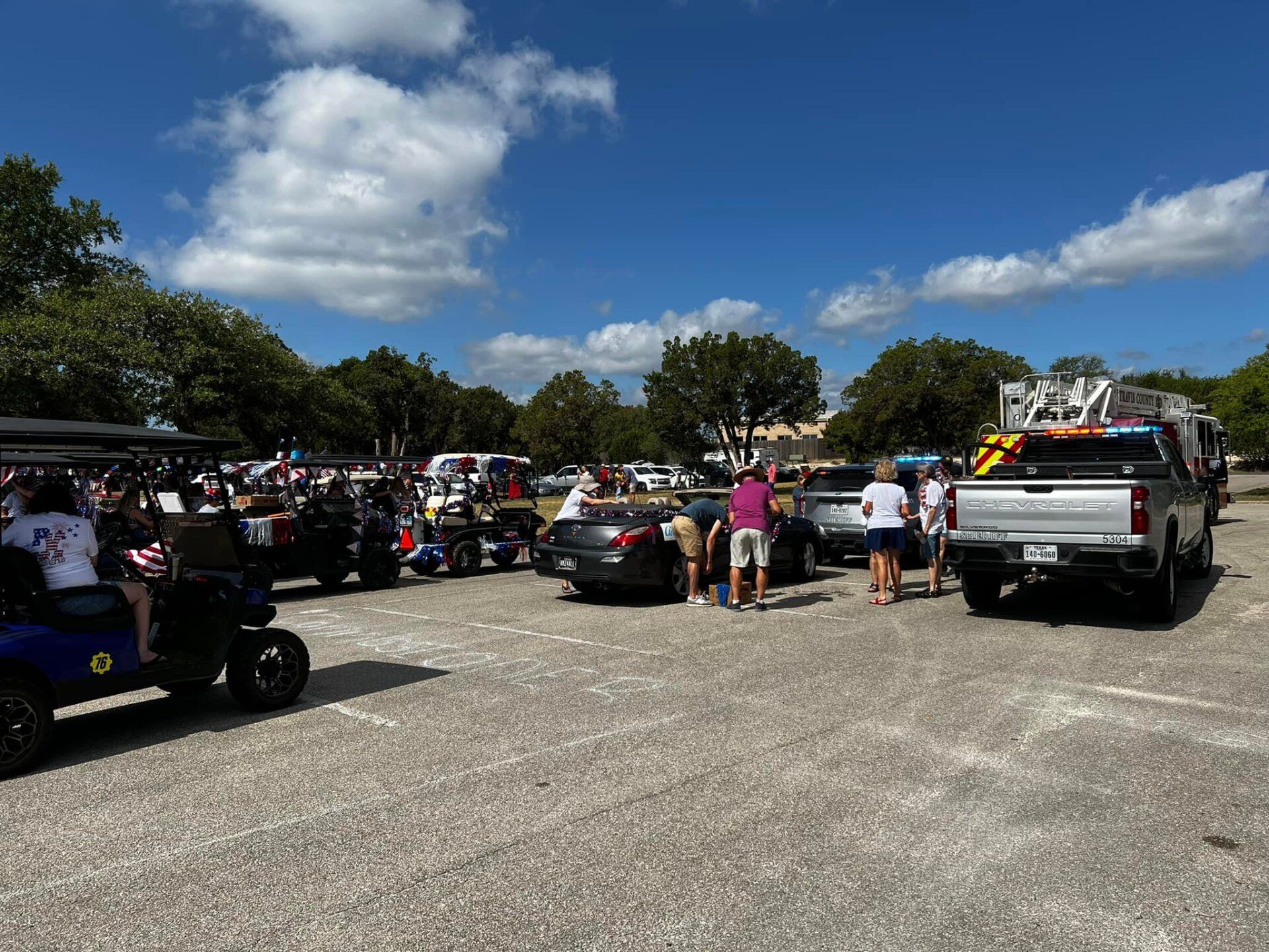 A parking lot filled with cars and golf carts on a sunny day.