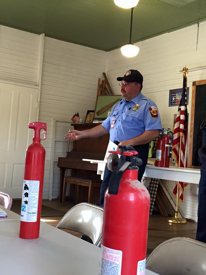 A fire fighter is training a group on fire extinguisher