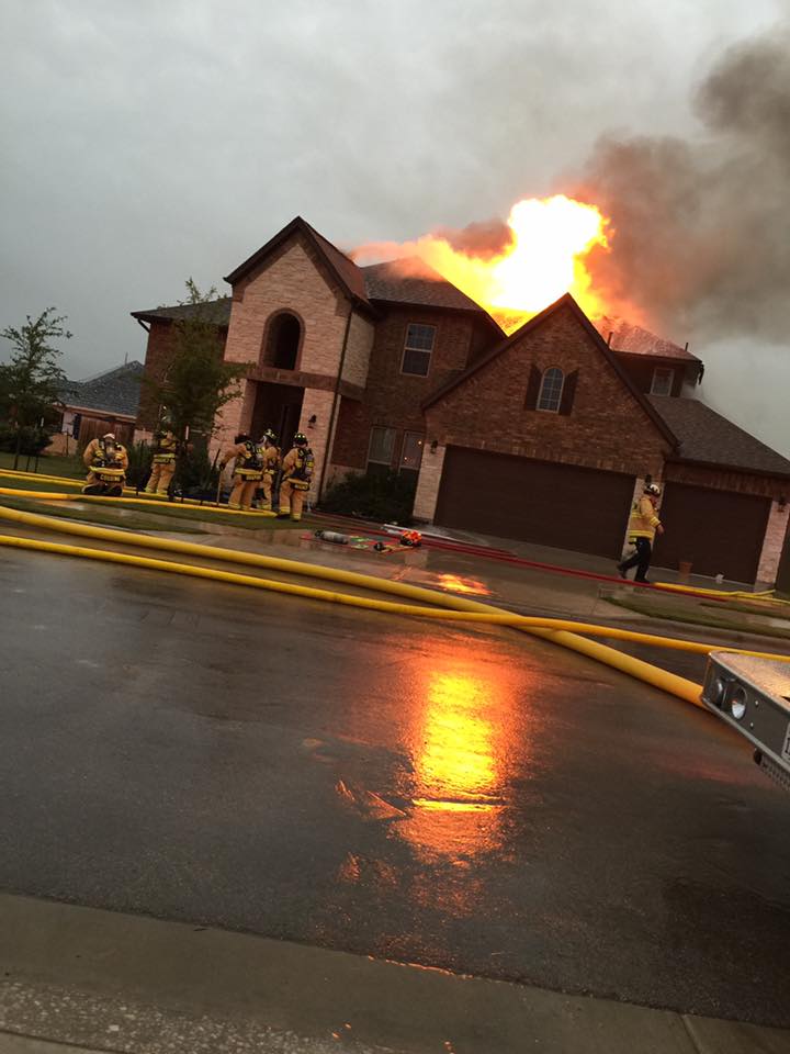 A group of fire fighters are working on putting out a house that is on fire.