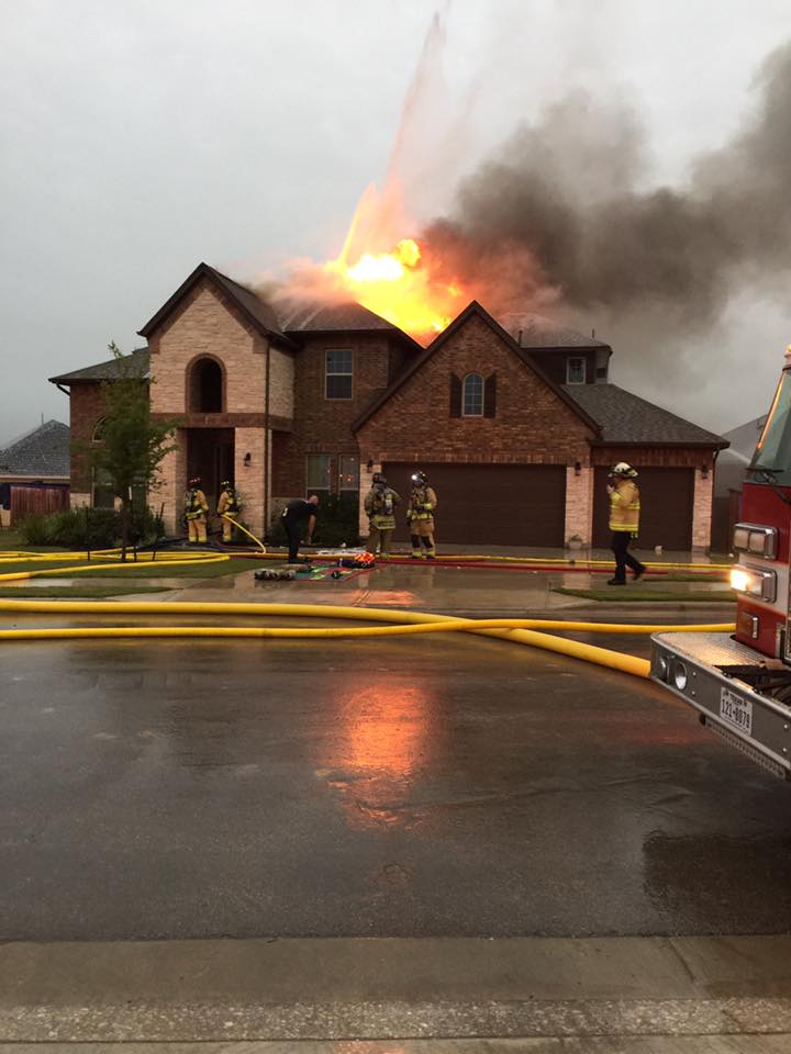 A group of fire fighters are working on putting out a house that is on fire.