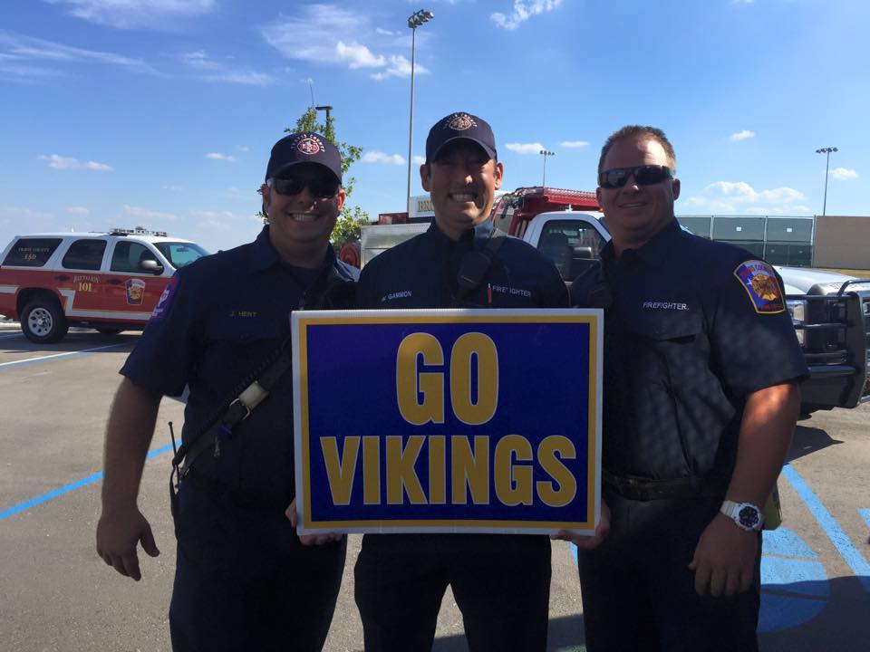 Three men holding a sign that says go vikings
