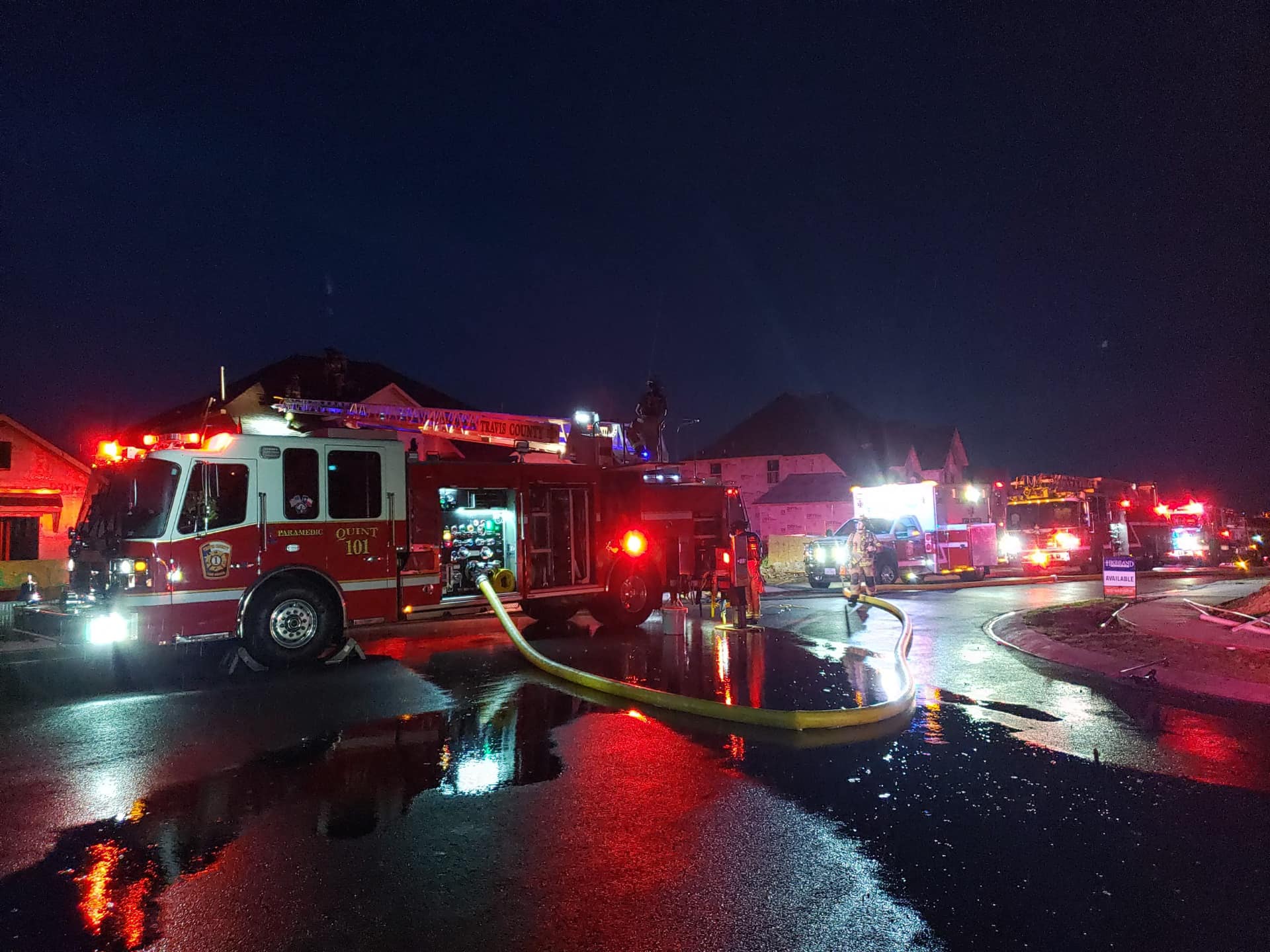 A fire truck is parked in front of a house at night.