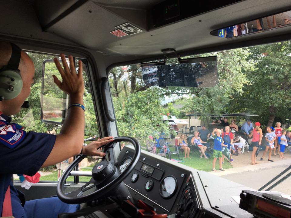 A man wearing headphones is driving a fire truck.