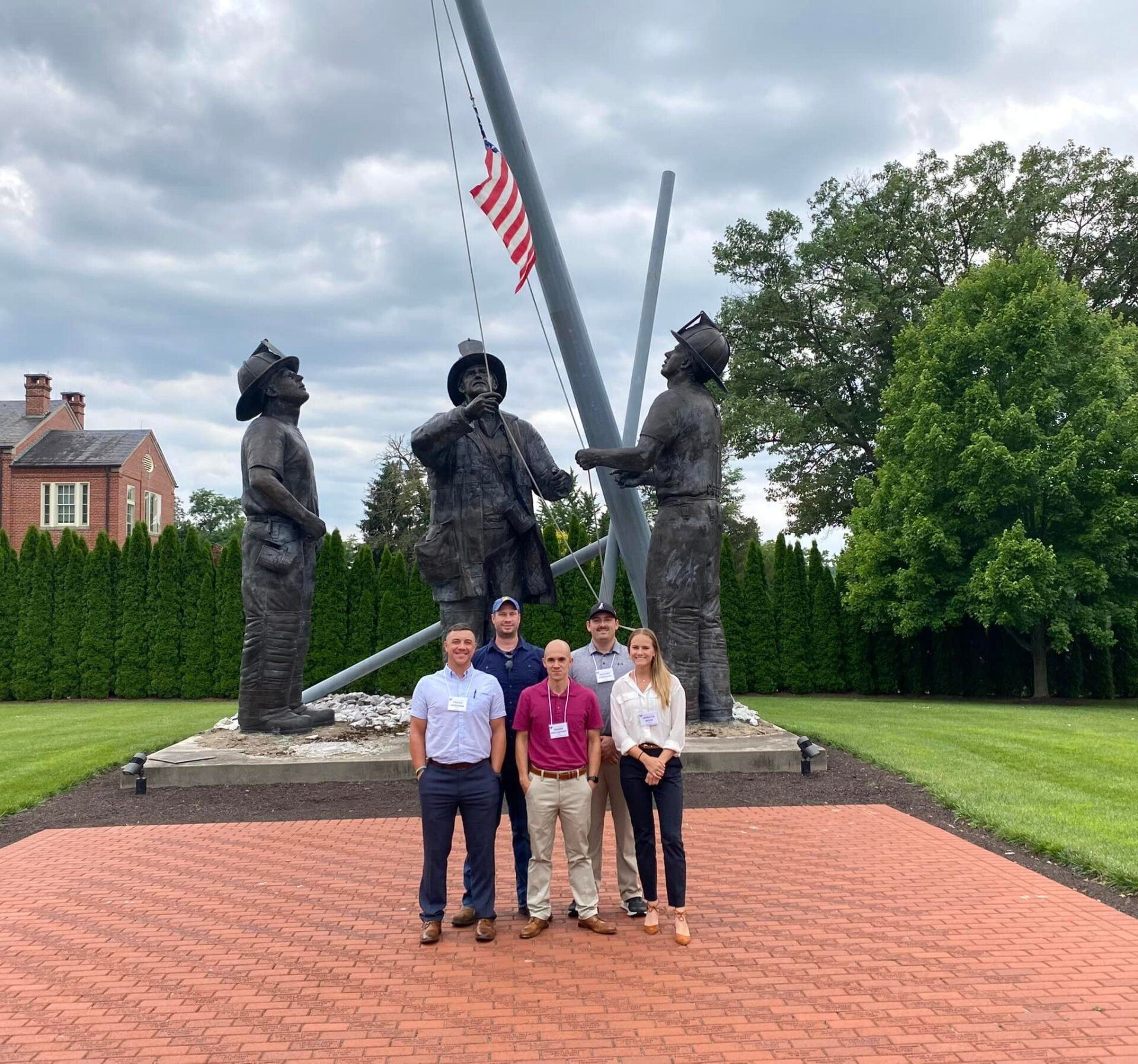 A group of people standing in front of a statue of a fireman