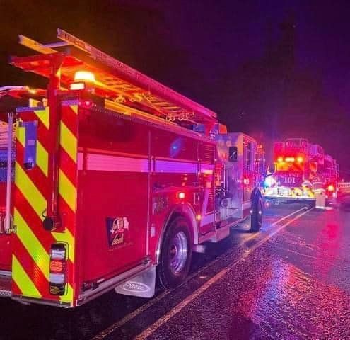 A fire truck is parked on the side of the road at night.