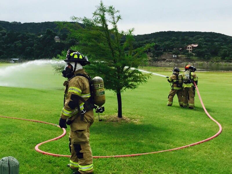 A group of firefighters are spraying water from a hose in a field.