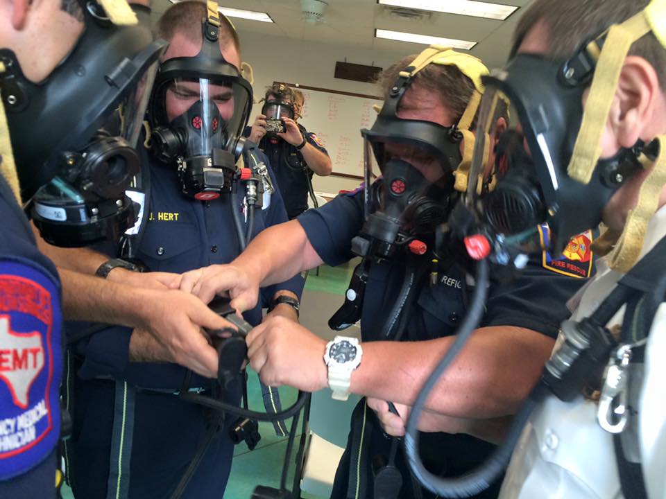 A group of firefighters are wearing breathing masks in a room.