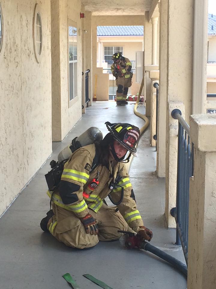 Two firefighters are working on a hose in a hallway.
