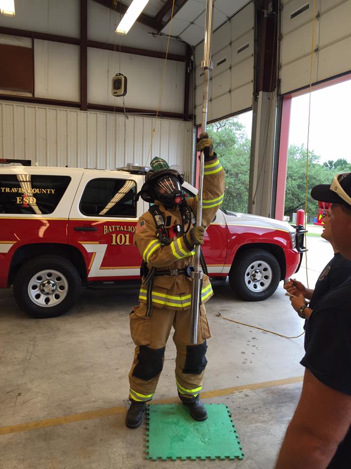 A fireman is standing in front of a fire truck during a physical agility test.