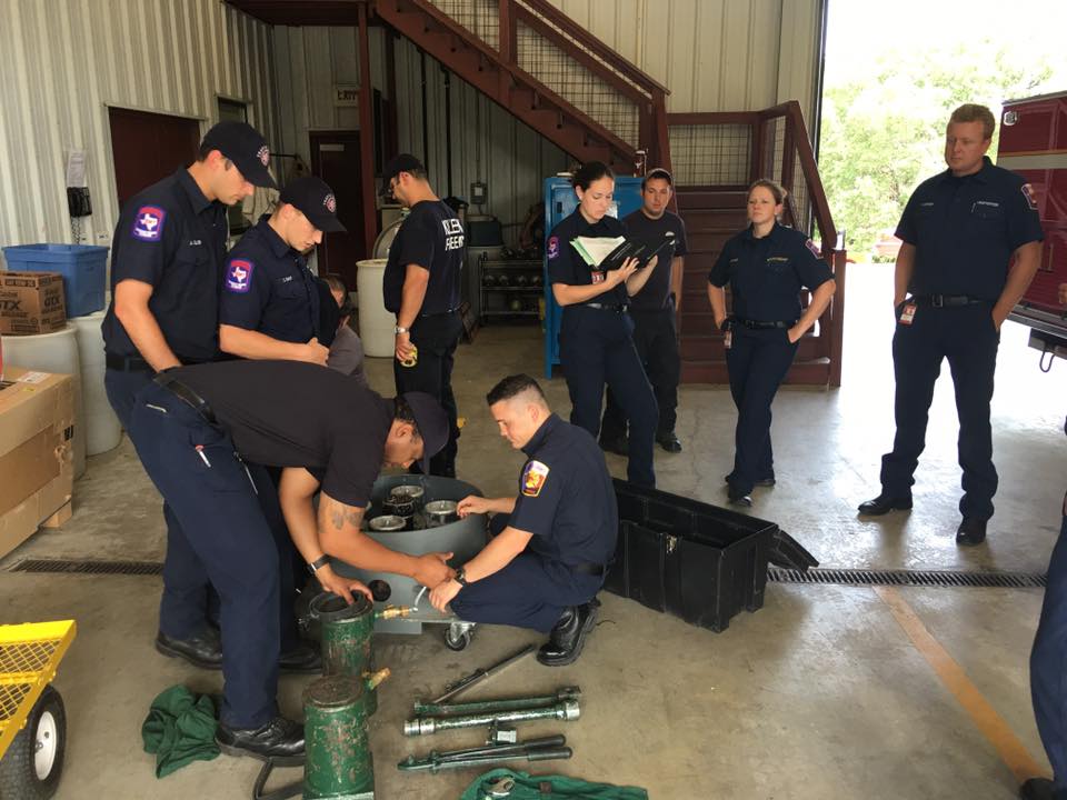 A group of firefighters are working on a machine in a garage.