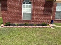 Brick house with a small garden bed and green grass.
