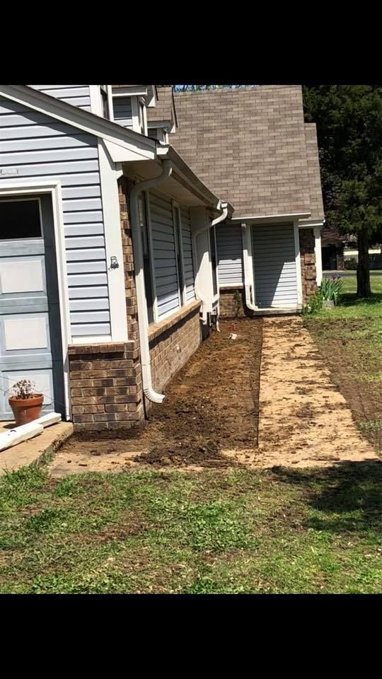 Side of a house with blue siding and a brick base; a muddy walkway leads to a side door.