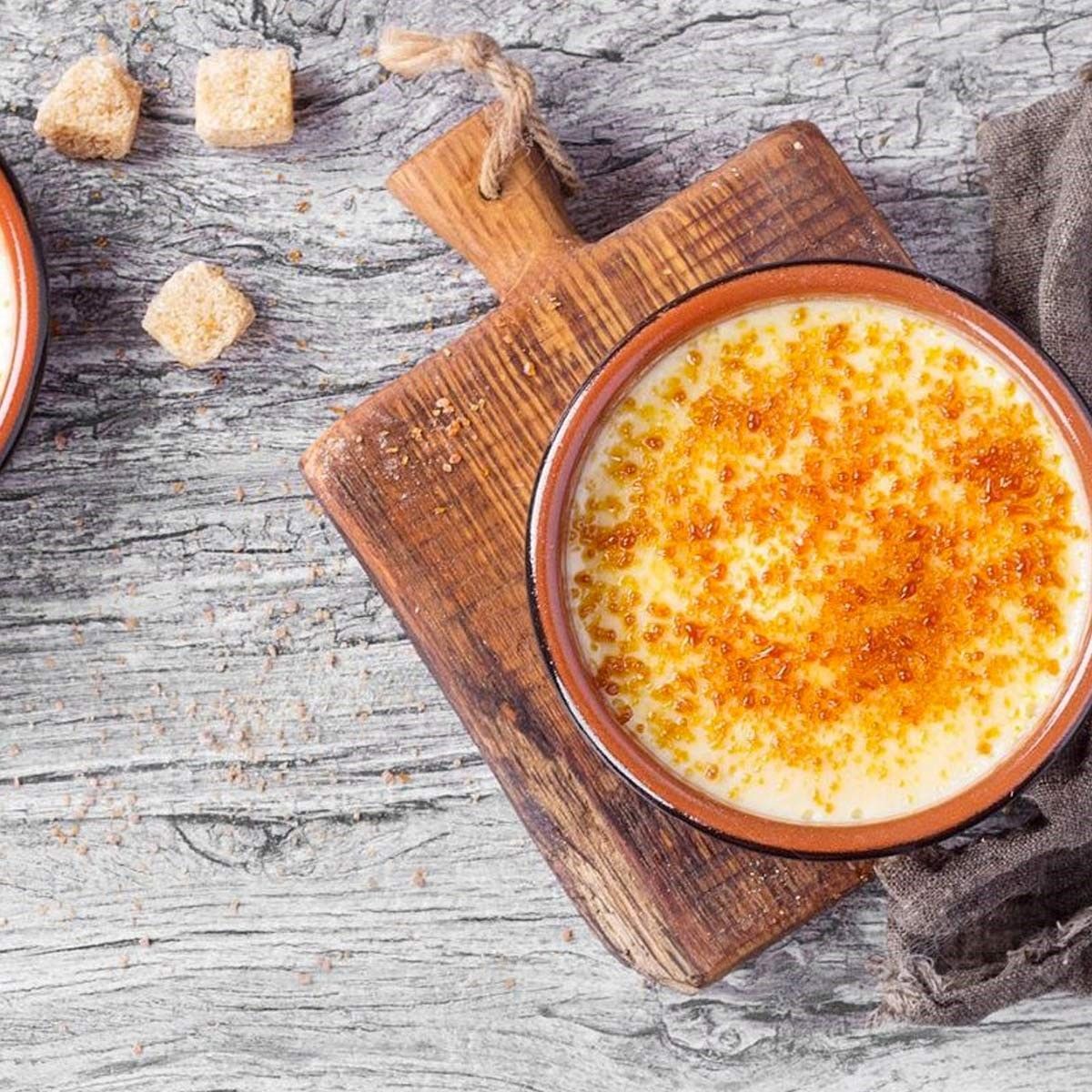 A bowl of soup is sitting on a wooden cutting board.