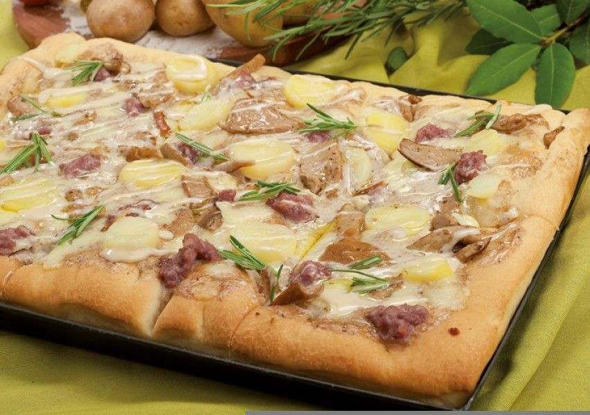 A pizza is sitting on a pan on a table.