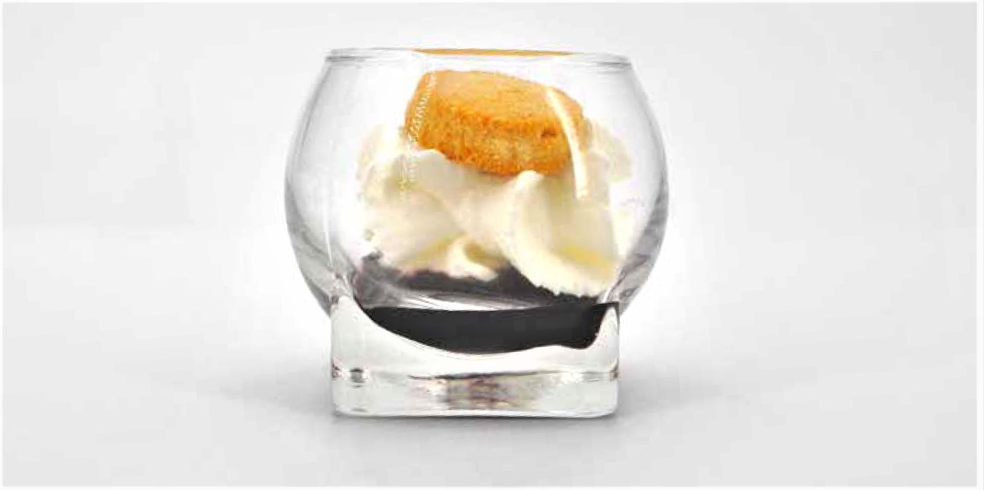 A glass filled with ice cream and a cookie on a white background.
