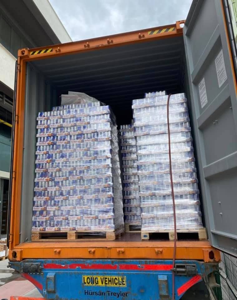 Shipping container loaded with pallets of Red Bull cans.