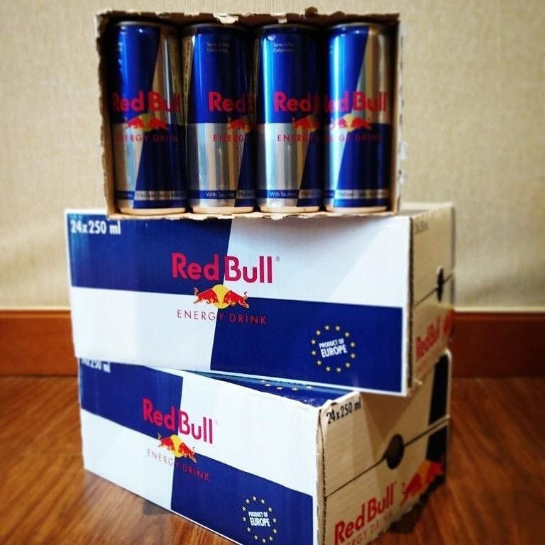 A stack of Red Bull energy drink cases with a partial carton of cans on top.