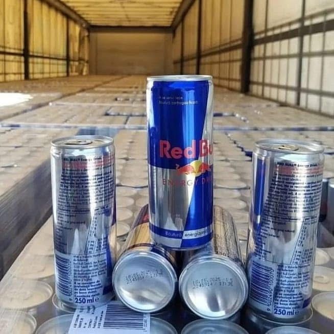 Red Bull energy drink cans stacked in a truck, one standing upright, the others on their sides.