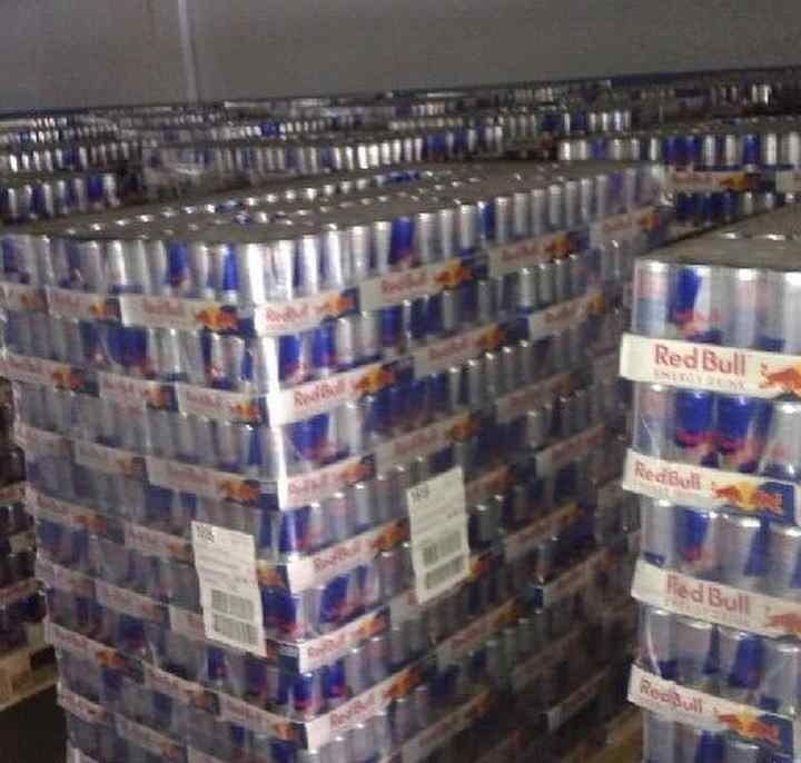 Pallets stacked with many cases of Red Bull energy drink cans in a warehouse.
