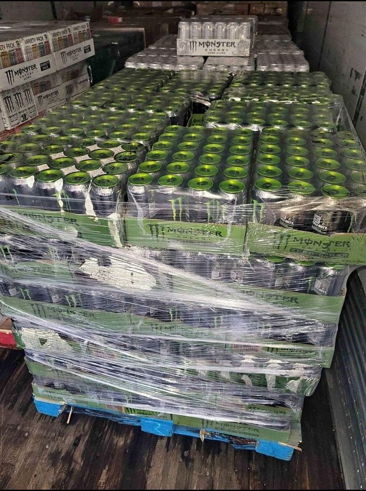 Pallets stacked with Monster energy drink cases in a truck. Green cans visible, wrapped in plastic.