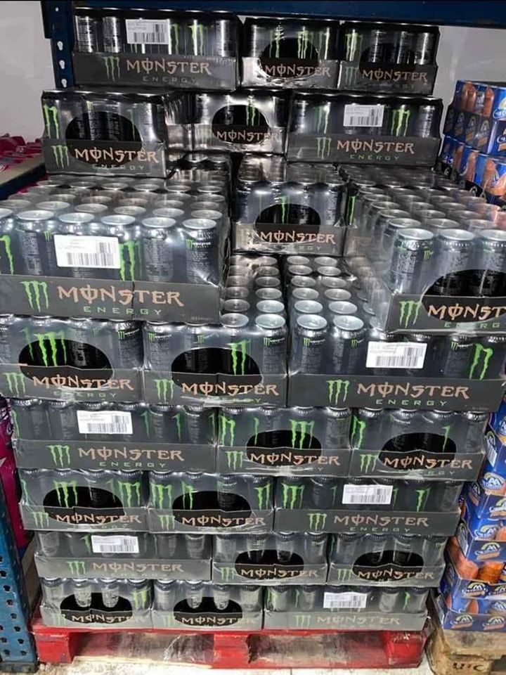 Pallet of Monster Energy drink cases stacked high in a store.