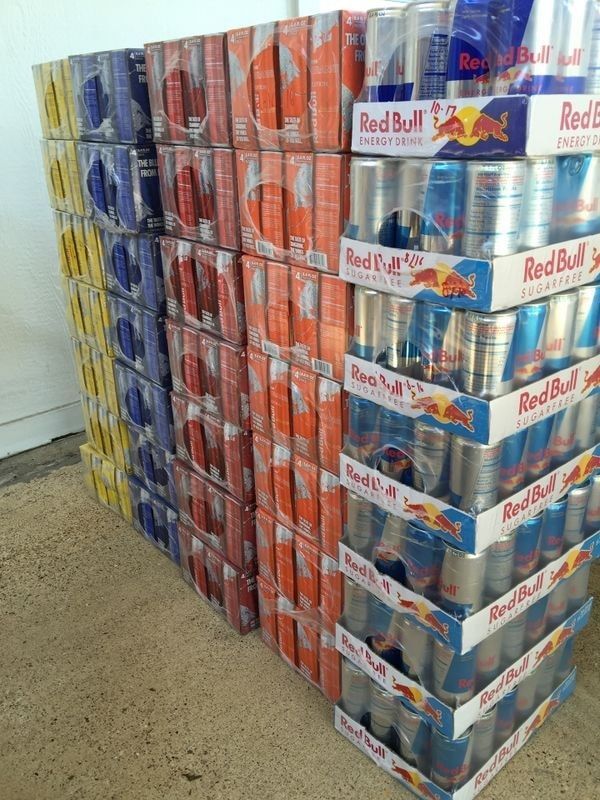 Stacks of Red Bull energy drink cases in various colors.