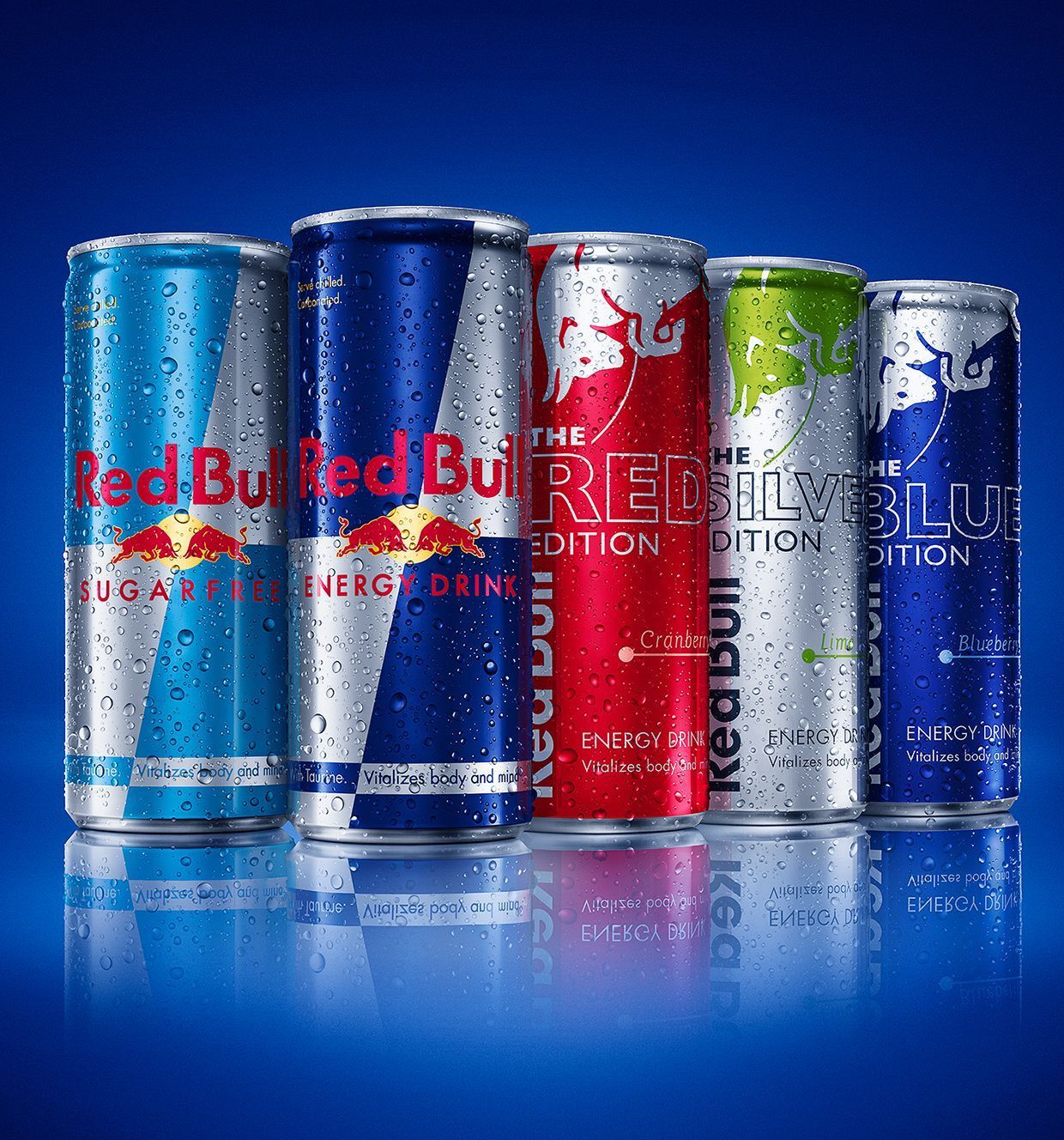 Five Red Bull energy drink cans: blue, red, silver, and green, with condensation against a blue backdrop.