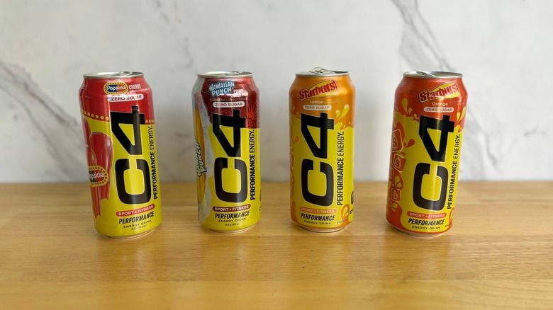 Four C4 Performance Energy drink cans lined up on a wooden surface.