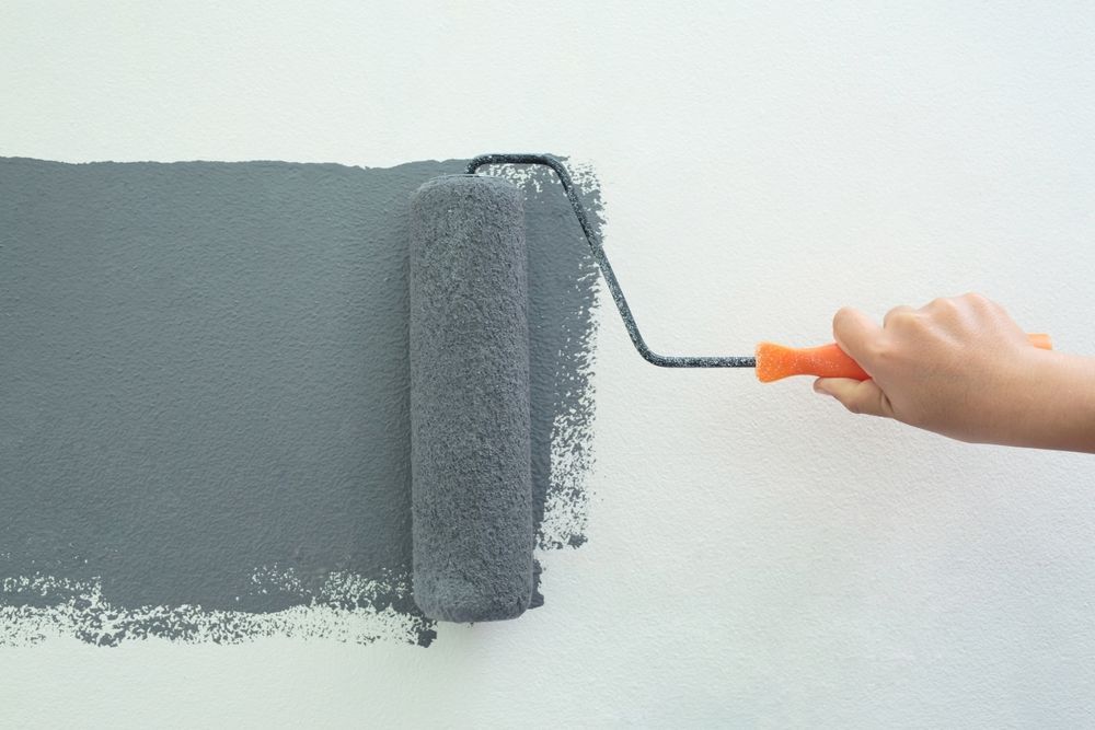 A person is painting a wall with a paint roller.