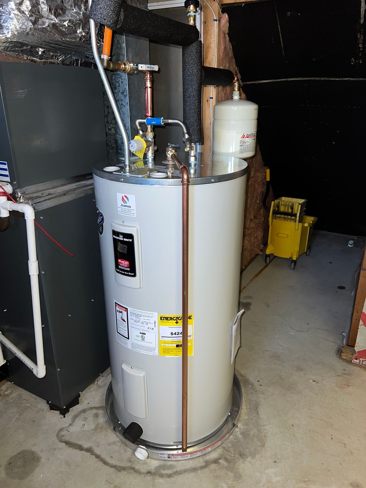 a water heater is sitting in a basement next to a furnace .