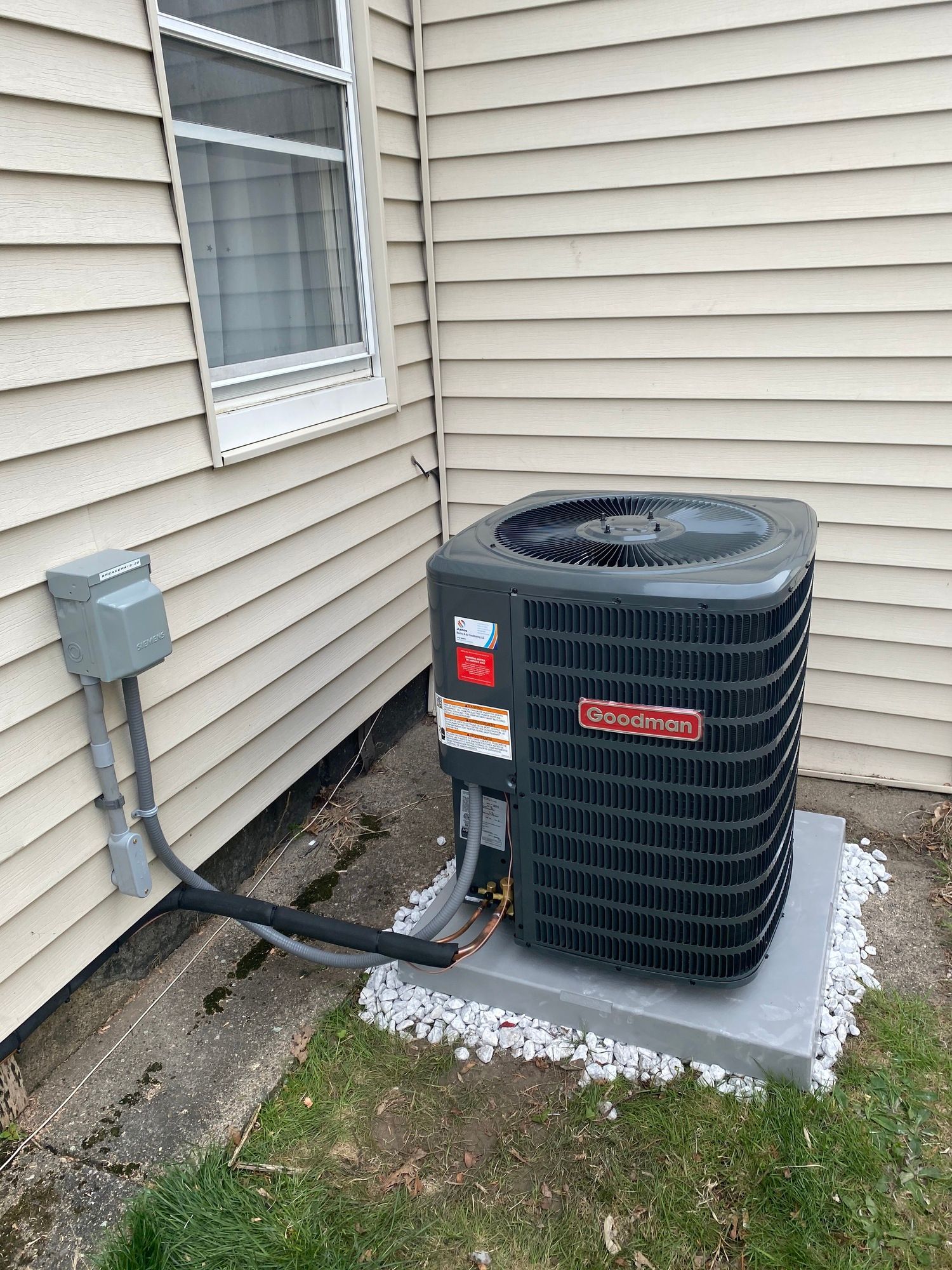 an air conditioner is sitting on the side of a house next to a window .