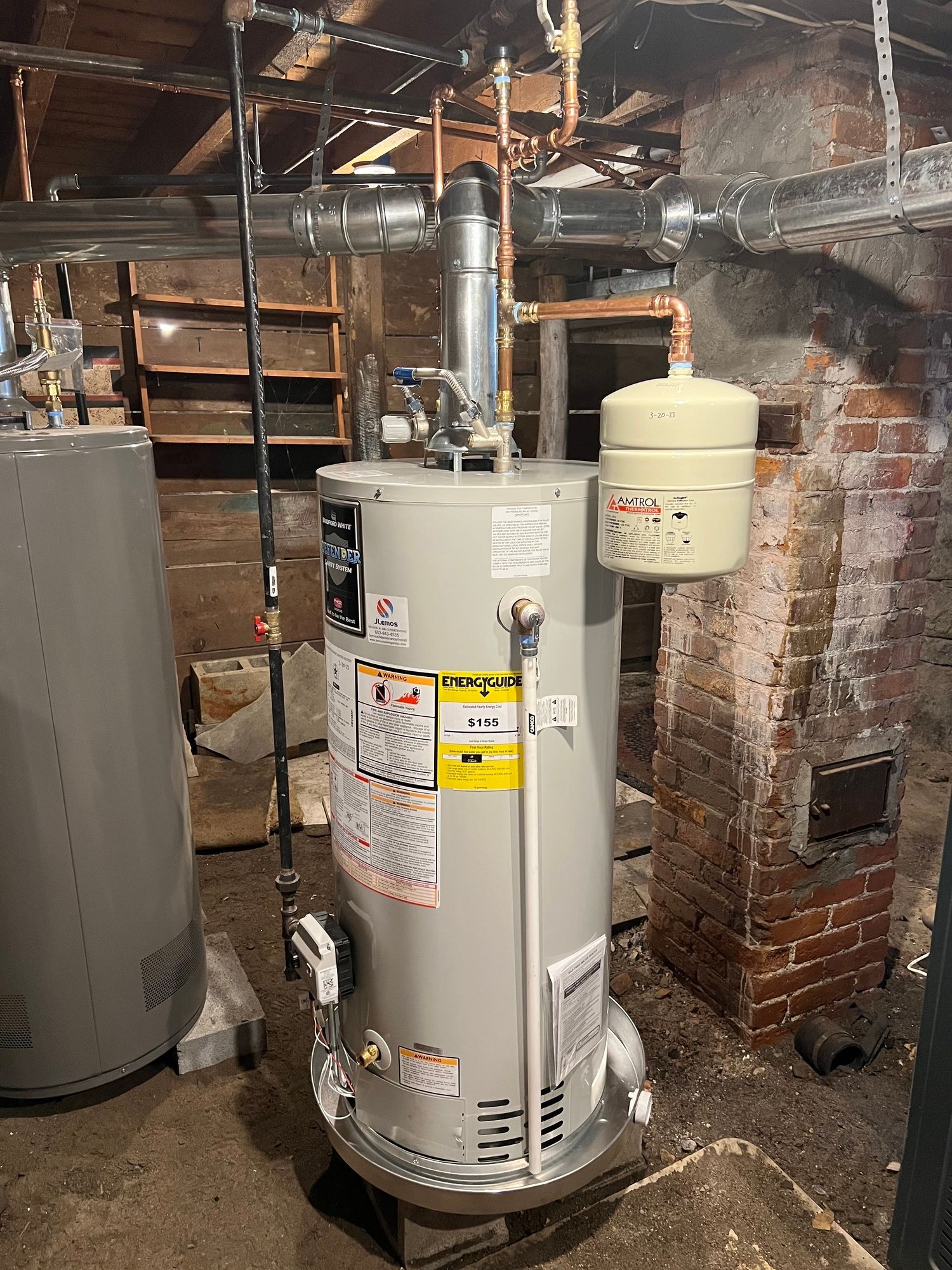 a water heater is sitting in a basement next to a brick wall .