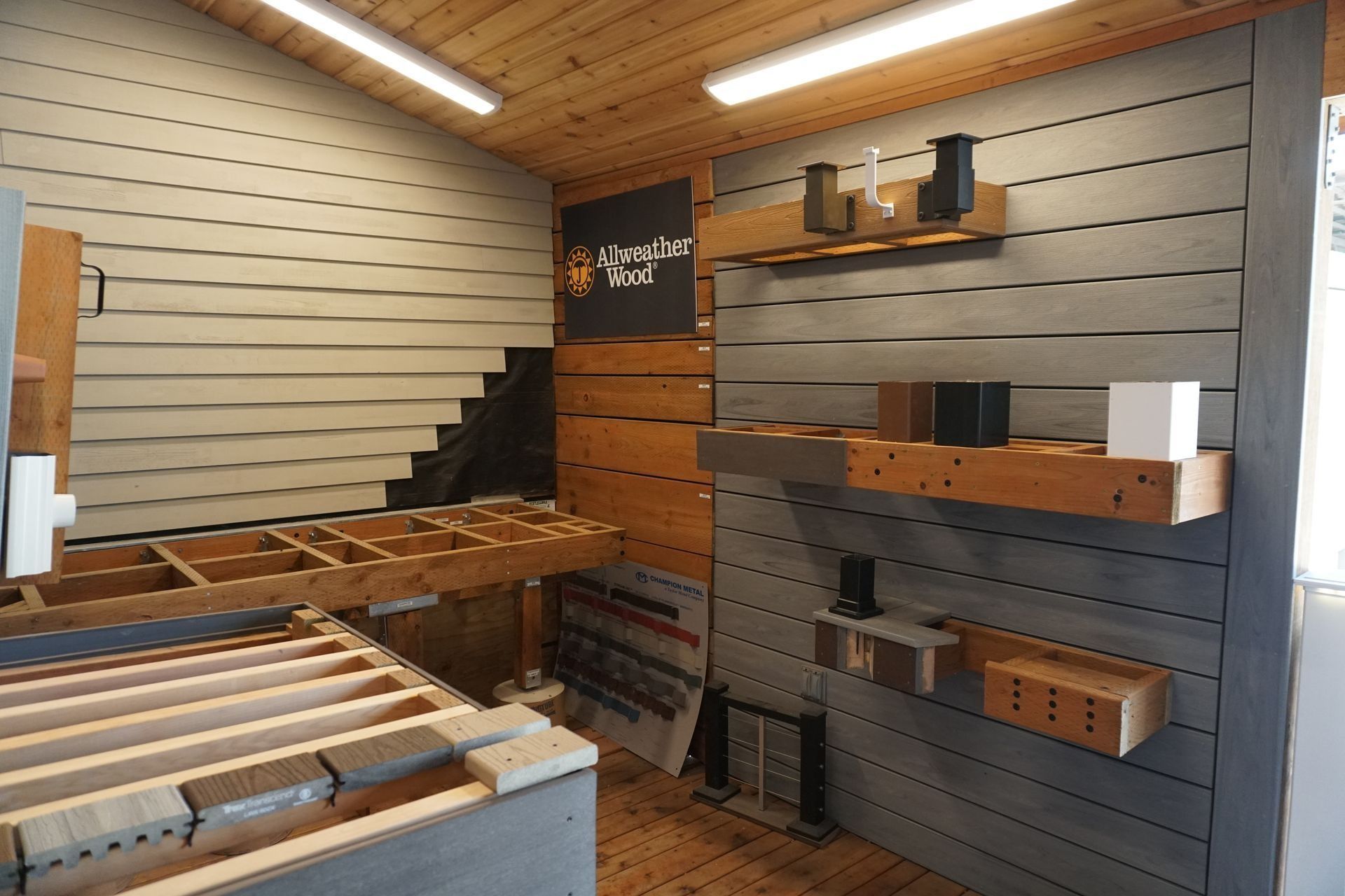 Interior of a display room, showcasing various wood and composite building materials, with shelves and wall samples.