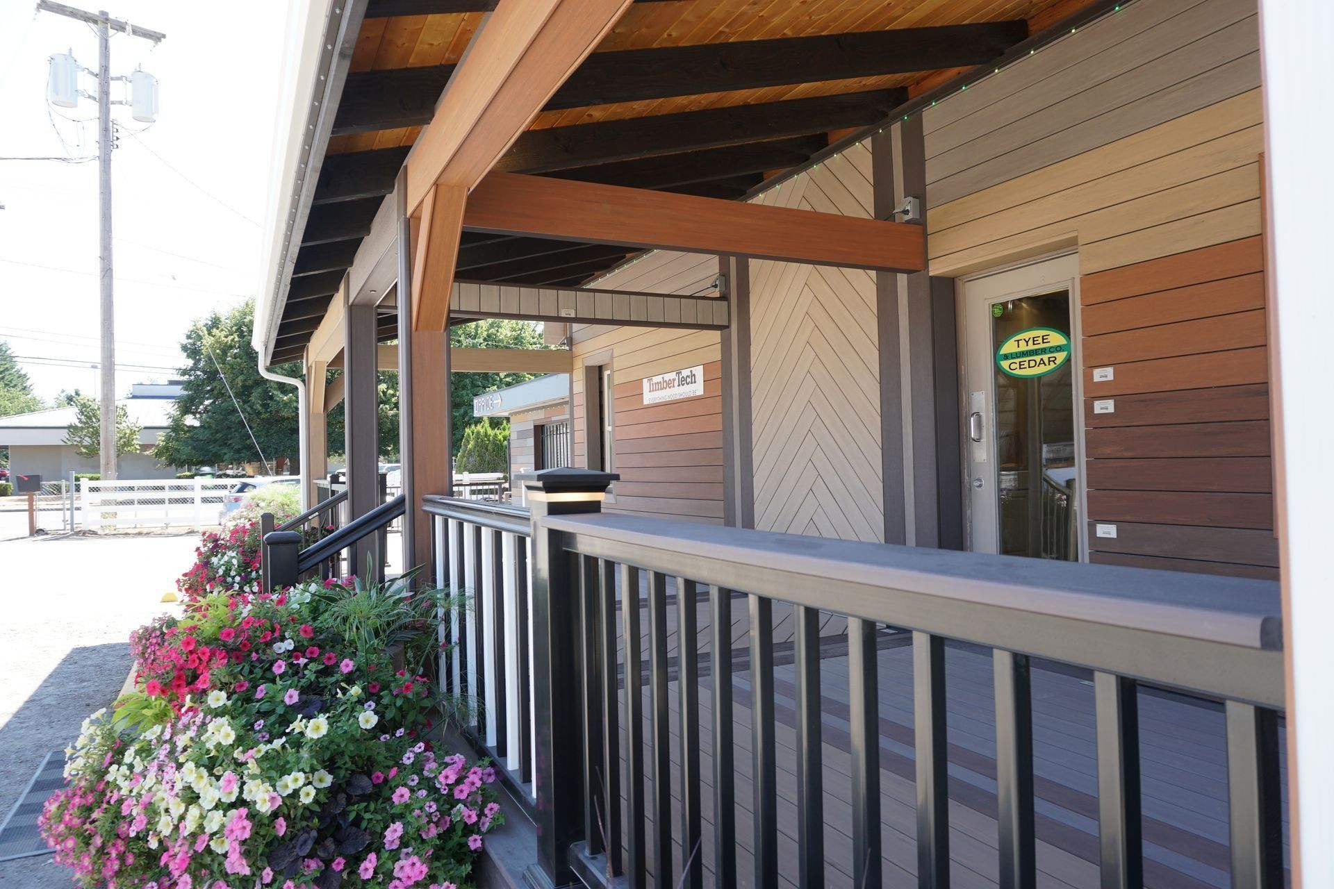 Exterior of a building with a wooden porch and flower boxes. Different colored siding.
