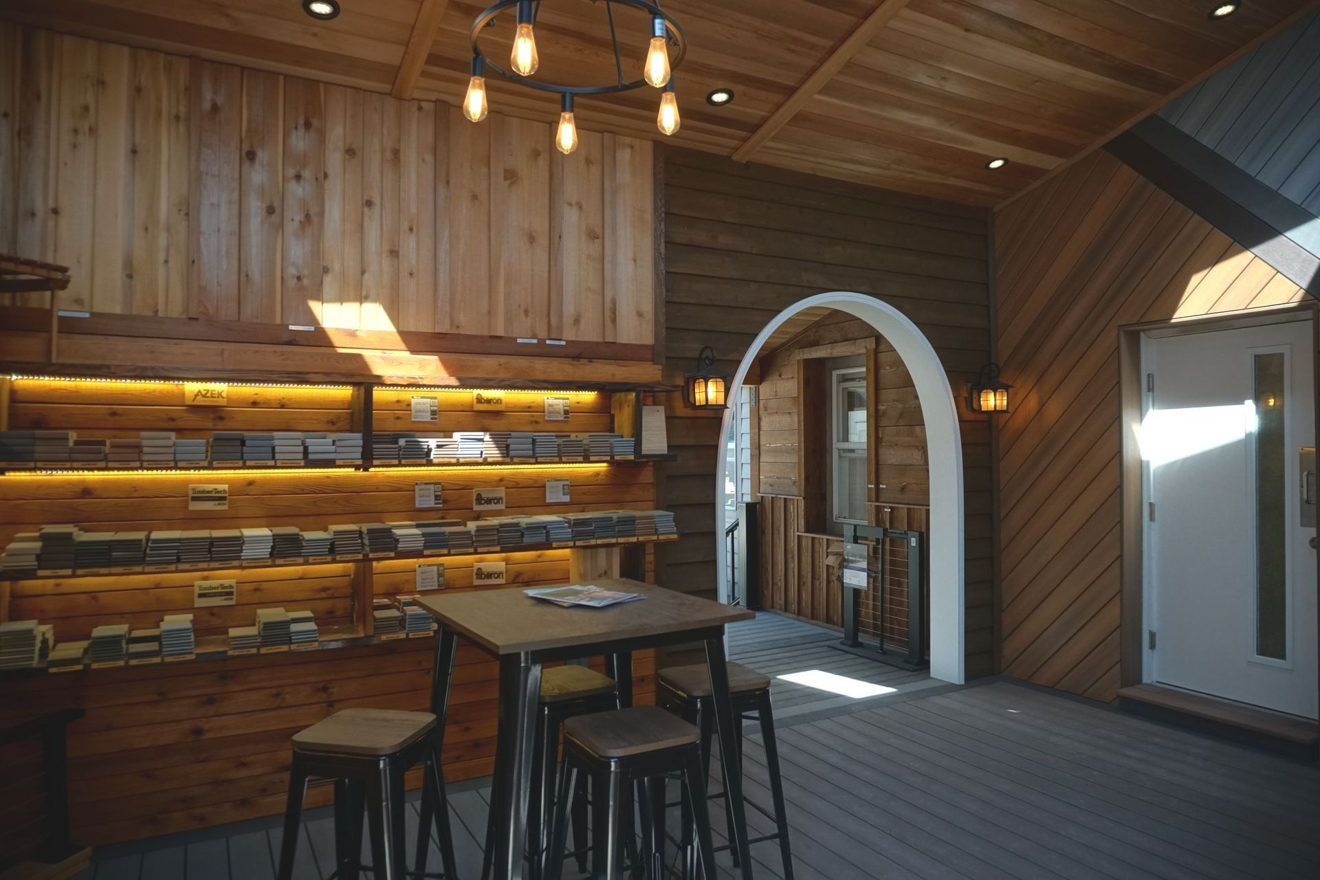 Cozy wooden interior with a display shelf, archway, and small table with stools. Warm lighting.