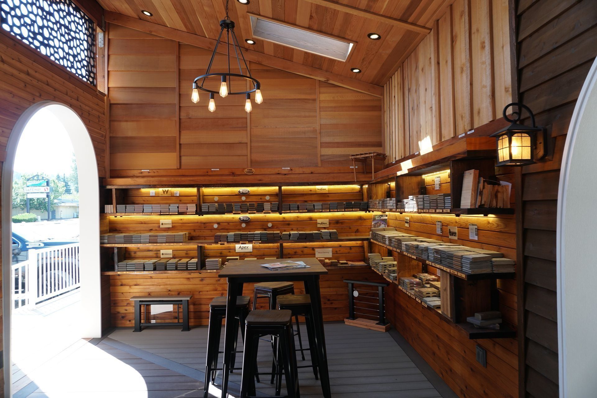 Wooden shop interior with shelves, merchandise, stools, and a black light fixture.